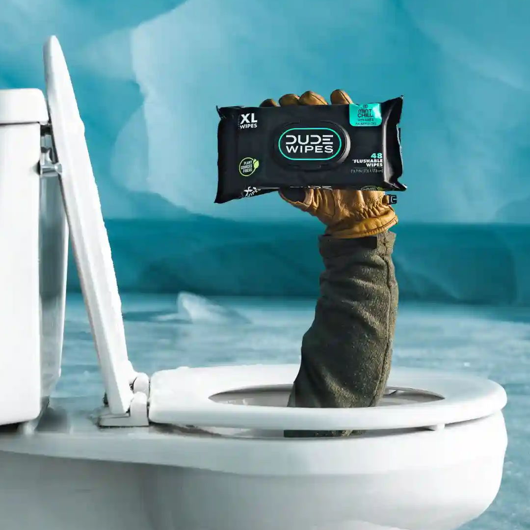 A gloved hand holding wipes emerges from a toilet.