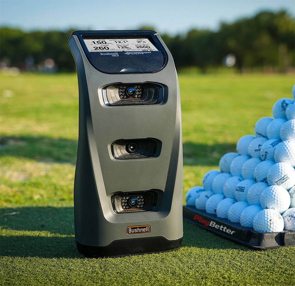 The Bushnell Launch Pro on the golf course next to a pyramid of golf balls