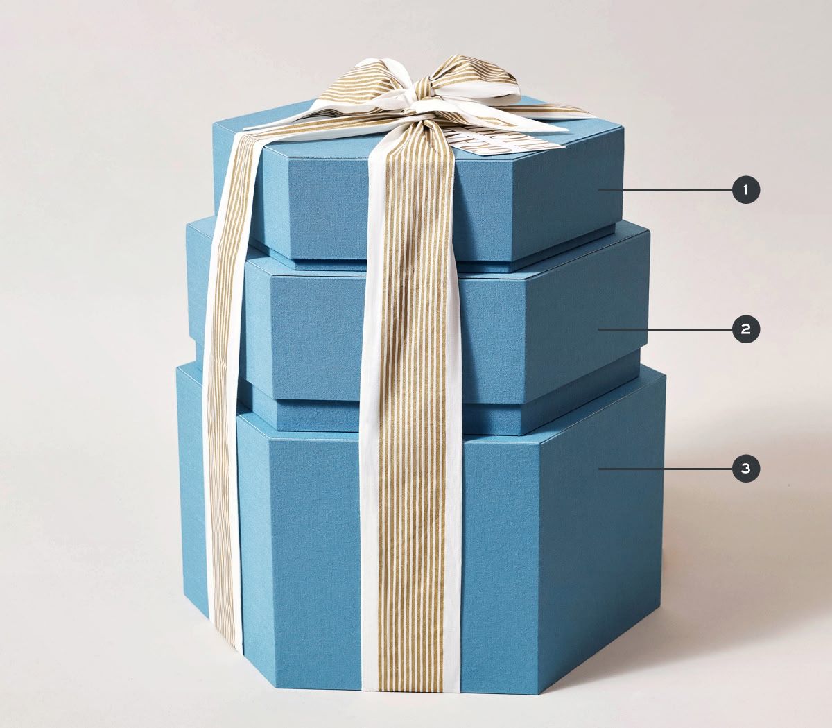 Three stacked blue gift boxes with a beige ribbon.