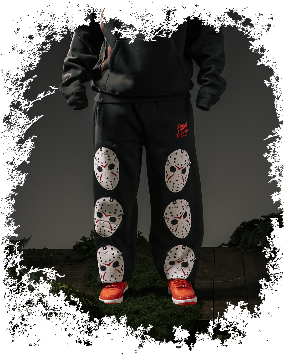 Person wearing black sweatpants with white mask designs and red sneakers.