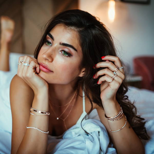 Model laying in bed wearing various Ring Concierge pieces.
