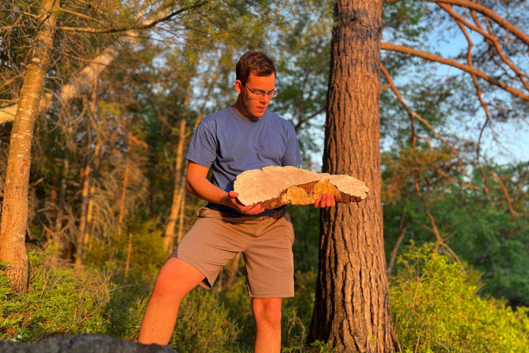 Garrett Kopp in the golden hour holding a large specimen of artist's conk mushroom or white reishi