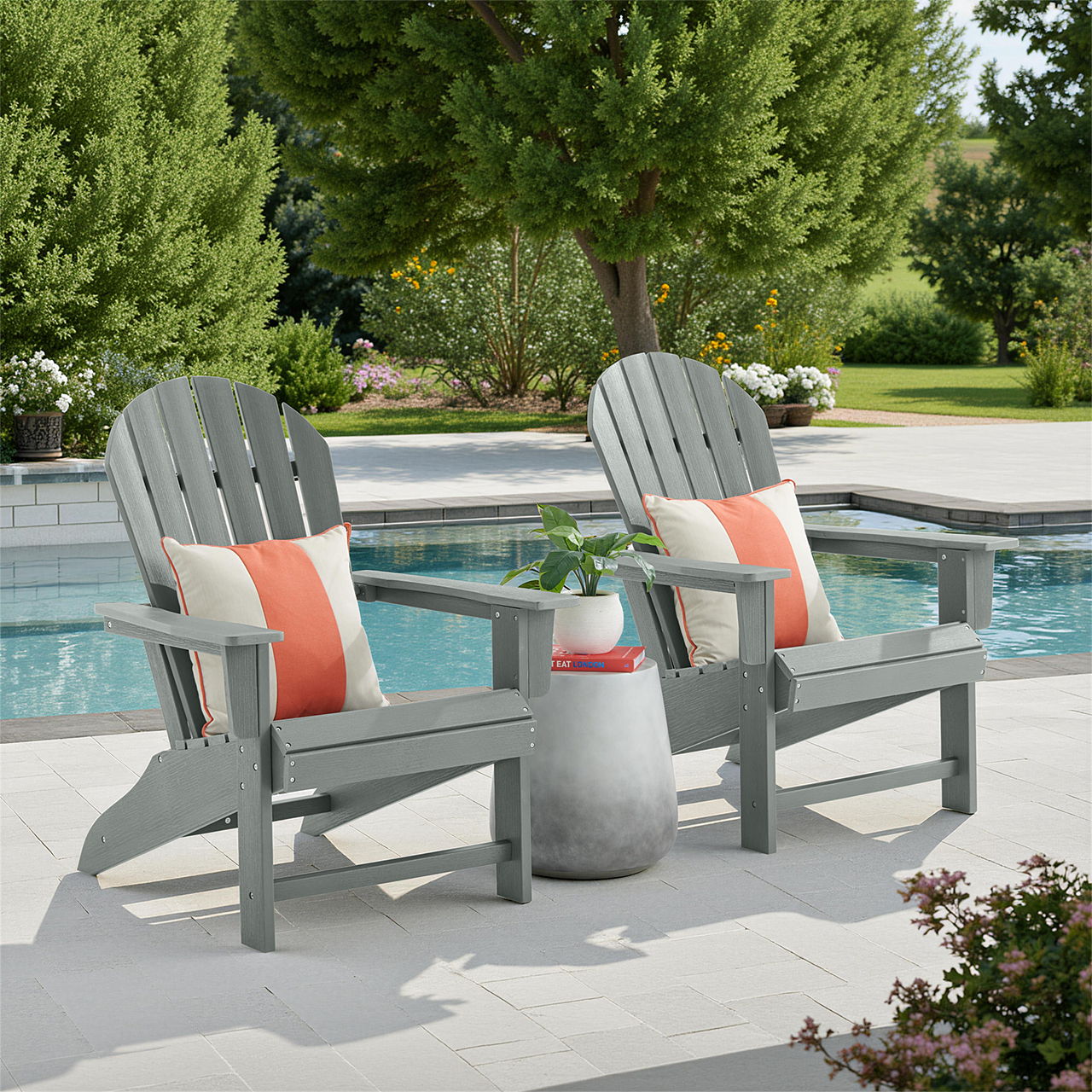 Two gray Adirondack chairs with cushions by a pool surrounded by greenery.