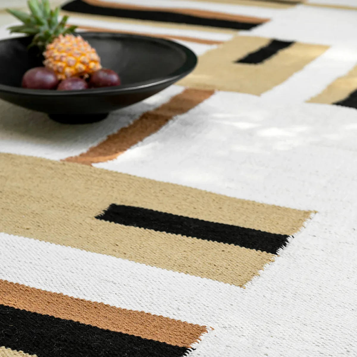 Modern flatweave geometric outdoor rug with black, cream, and tan pattern, offering a stylish low-maintenance rug option for covered patios. 
