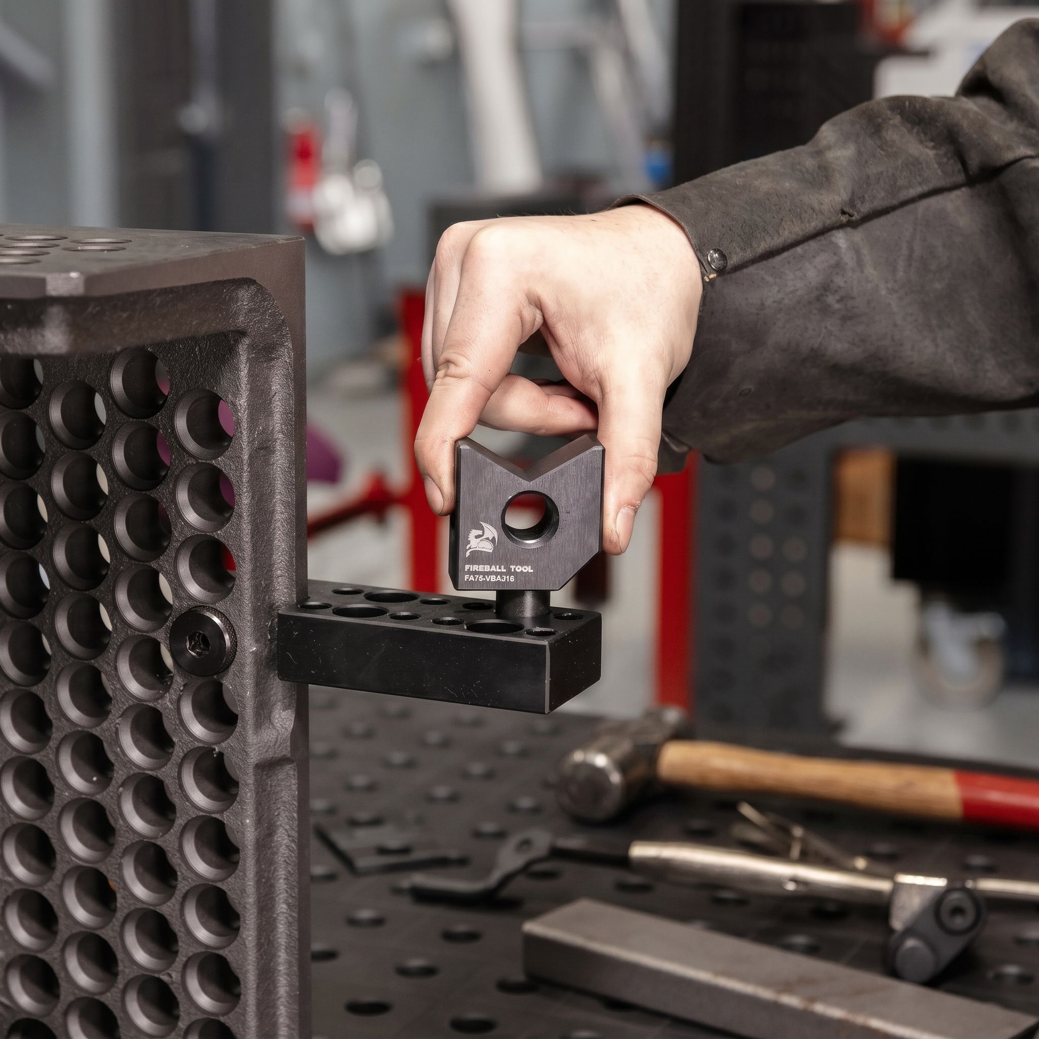 Person adjusting a tool on a workbench with various tools nearby.