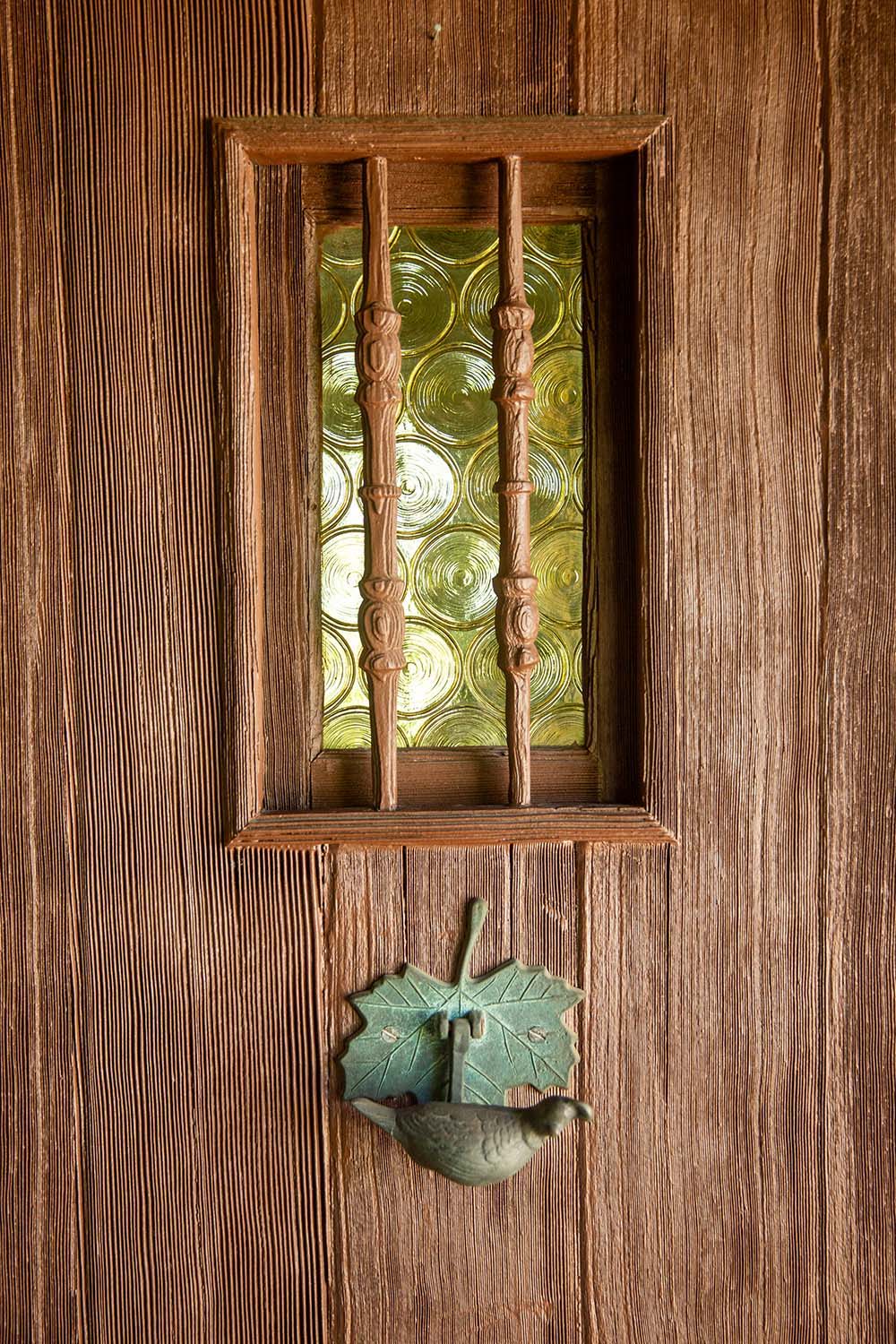 The front door of a vintage home with a speakeasy and a cast quail door knocker.