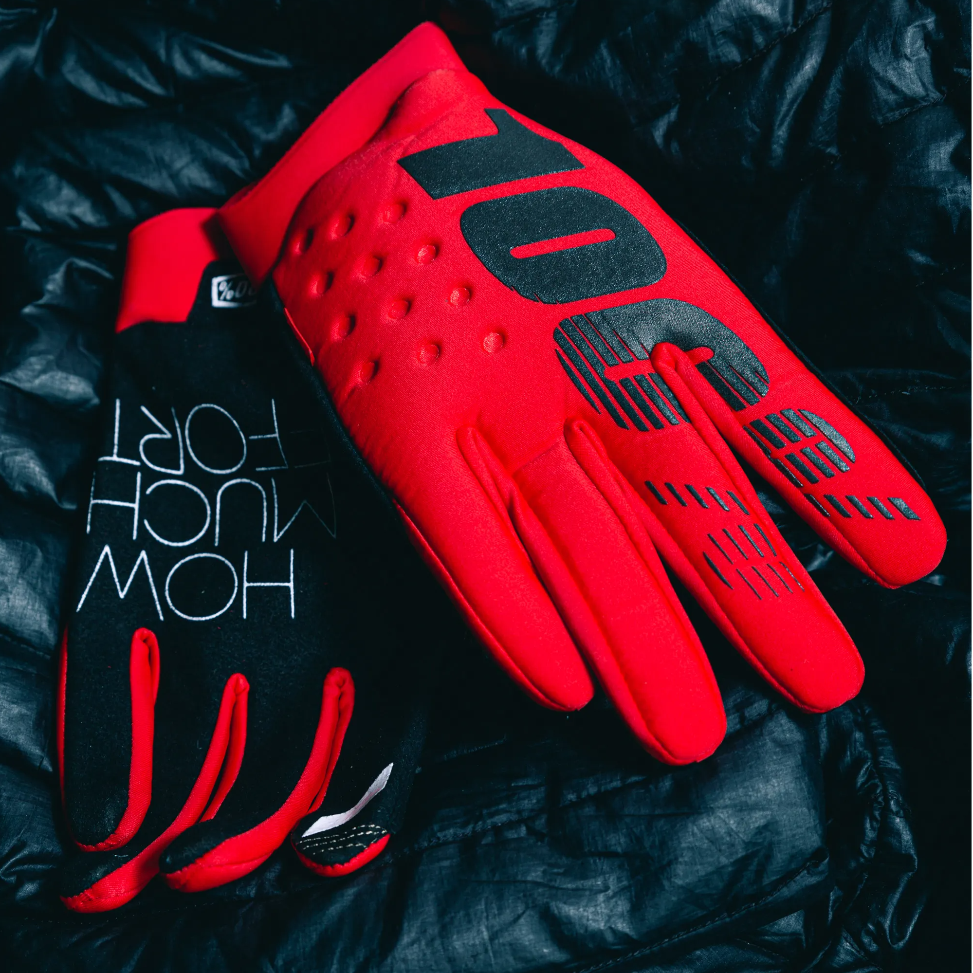 red 100% brisker mtb cold weather gloves sitting on a black puffy jacket