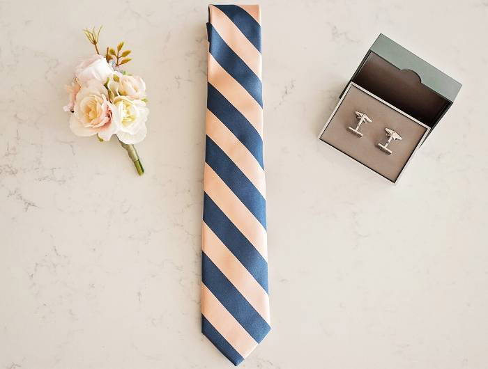 Dusty blue and pink striped tie with a boutonniere and cufflinks