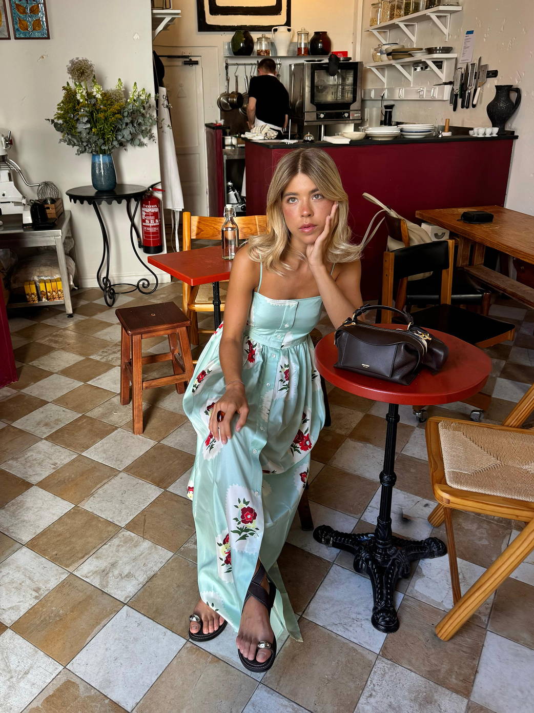 Model Ines, wearing a teal blue coloured maxi dress in a Lisbon cafe.