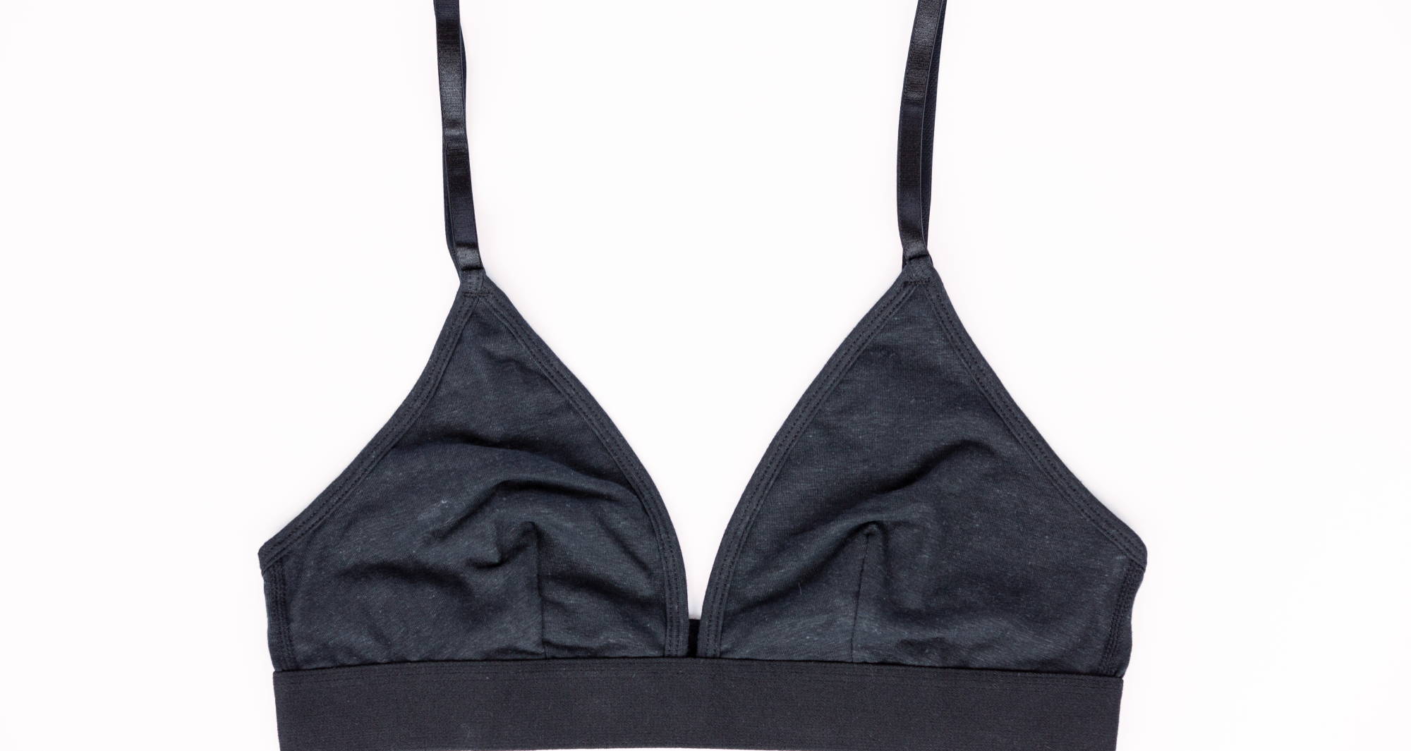 Black triangle bralette laid perfectly flat against a white background to show the parts of the bra