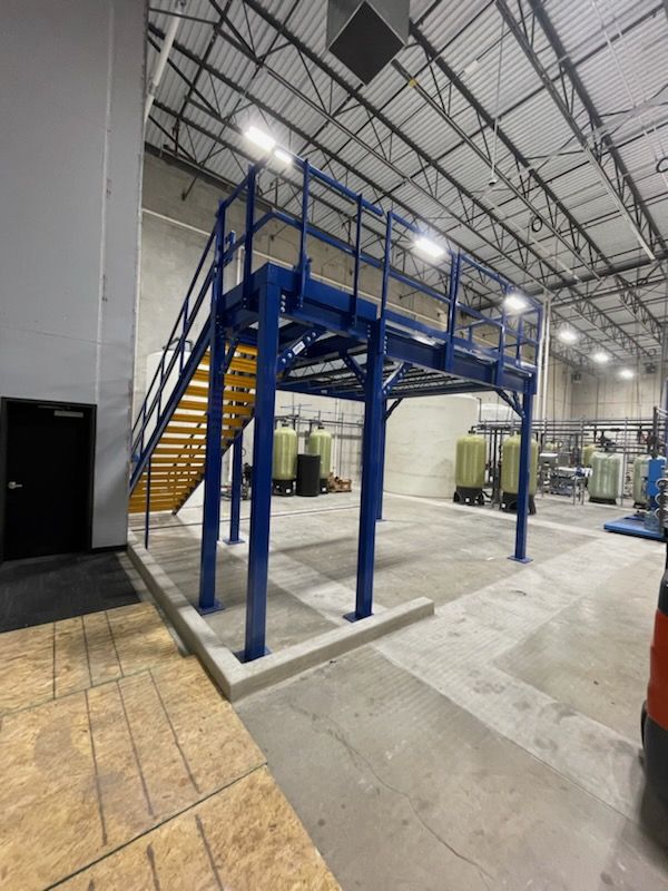 Industrial staircase with blue railing in a spacious warehouse.