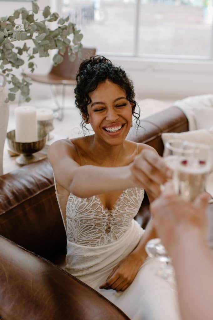 Une mariée portant une robe en dentelle finement détaillée qui fait tinter des coupes de champagne.