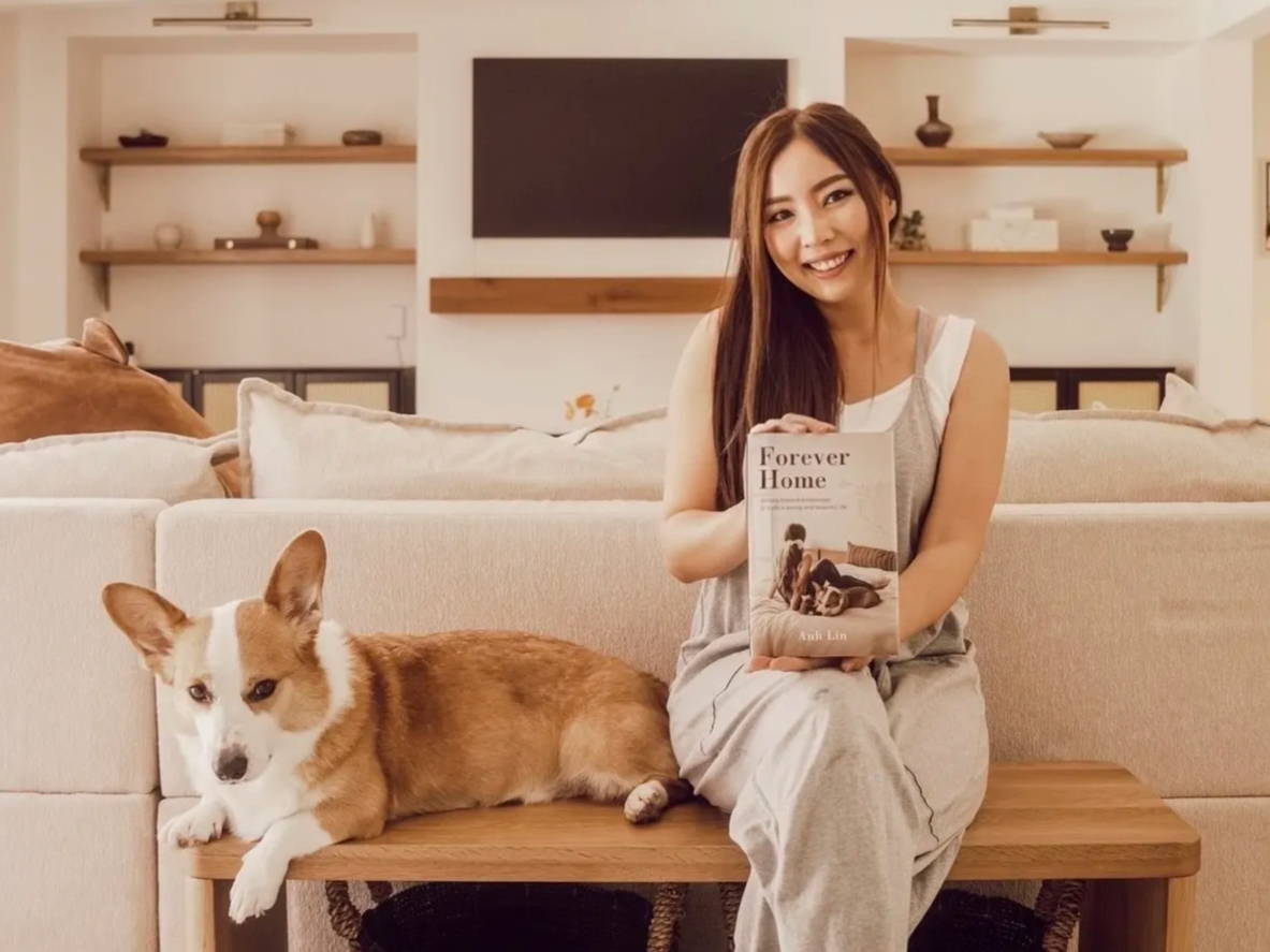 Anh Lin sitting with her dog while holding a copy of Forever Home