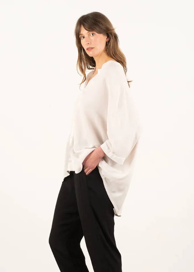 A model wearing an oversized, off white  shirt with black trousers