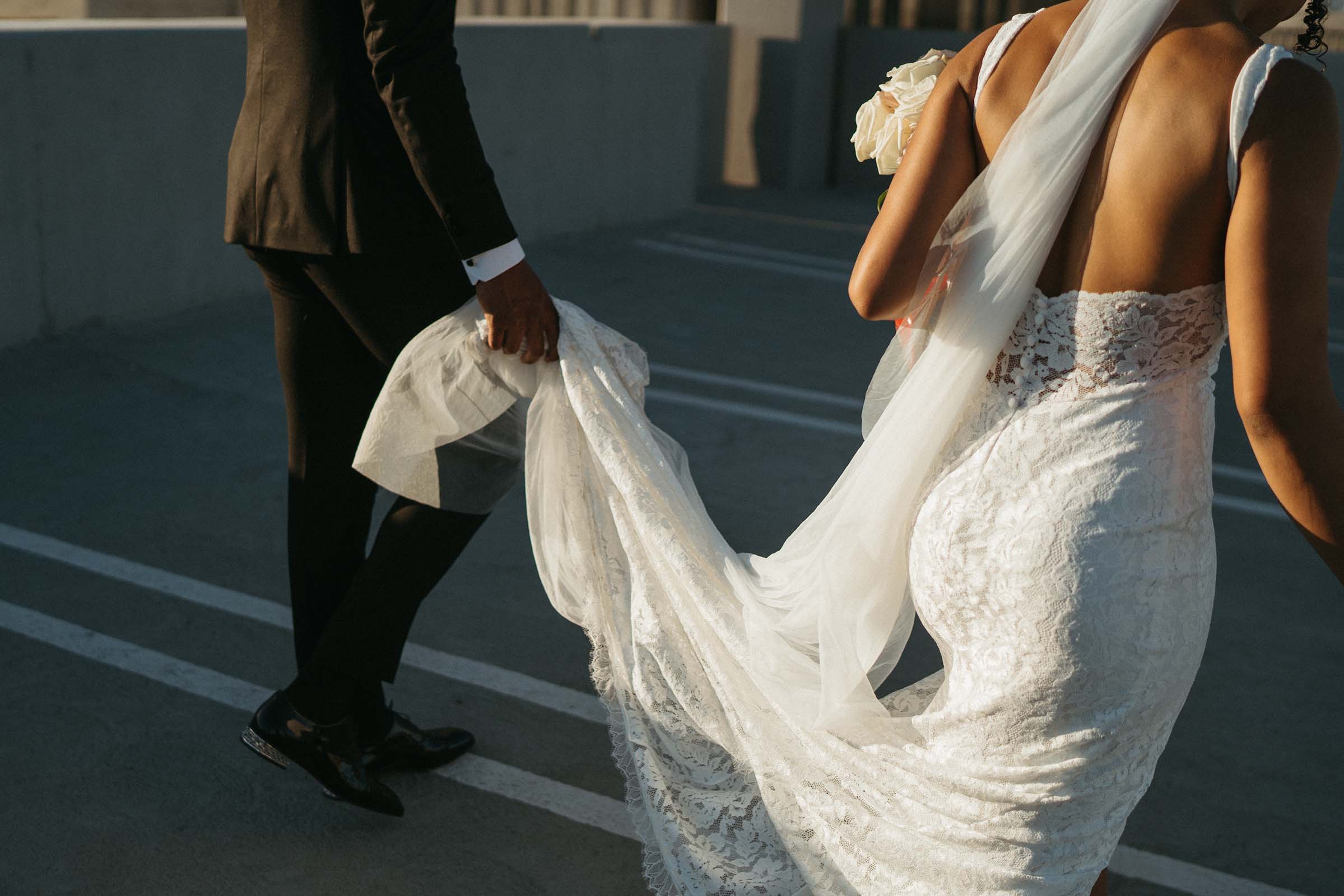 Groom holding brides gown train