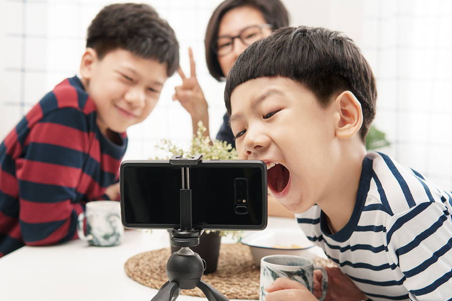 two boys and a mom in the background video calling on a black phone