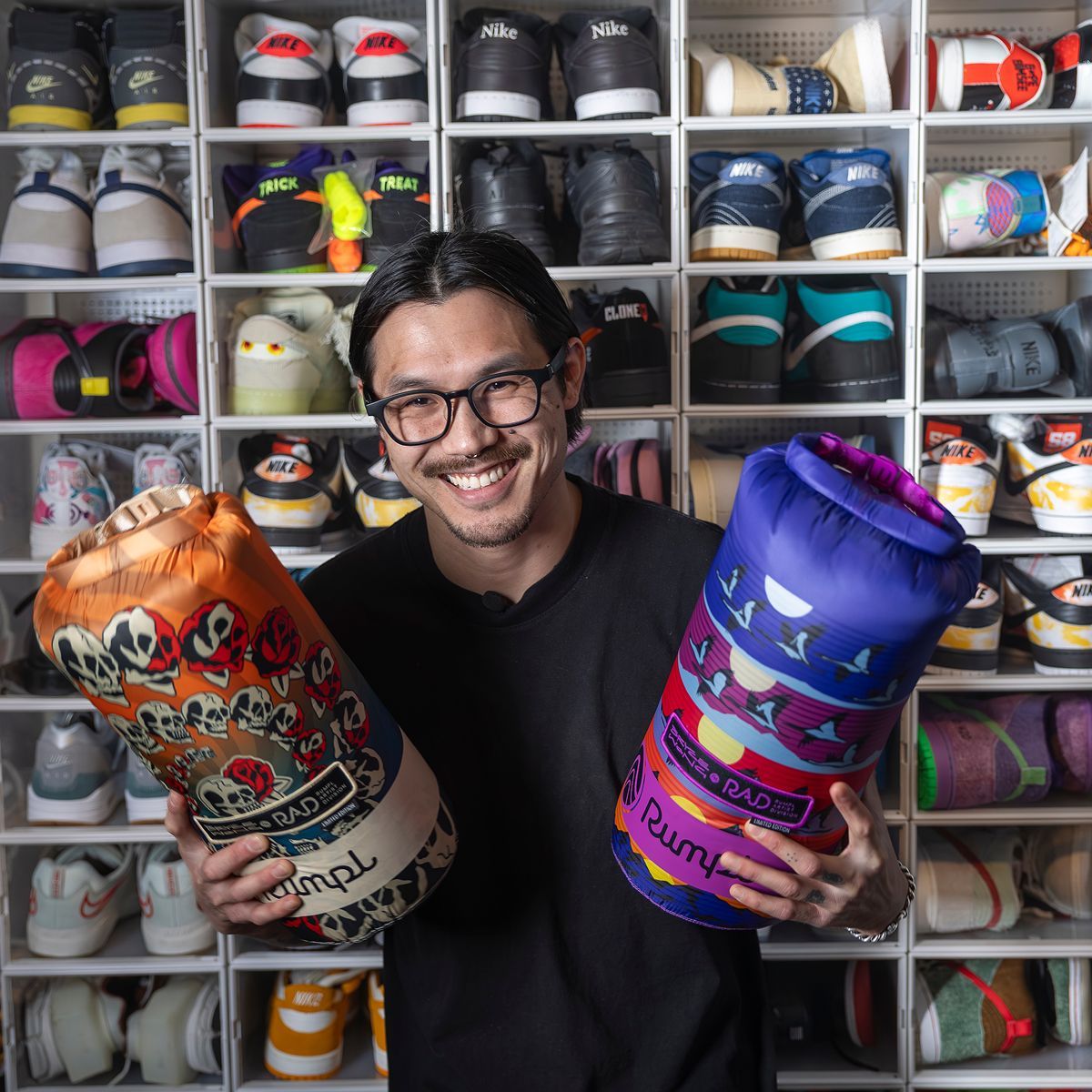 Bryce Wong holding two Rumpl blankets in front of a wall of shoes