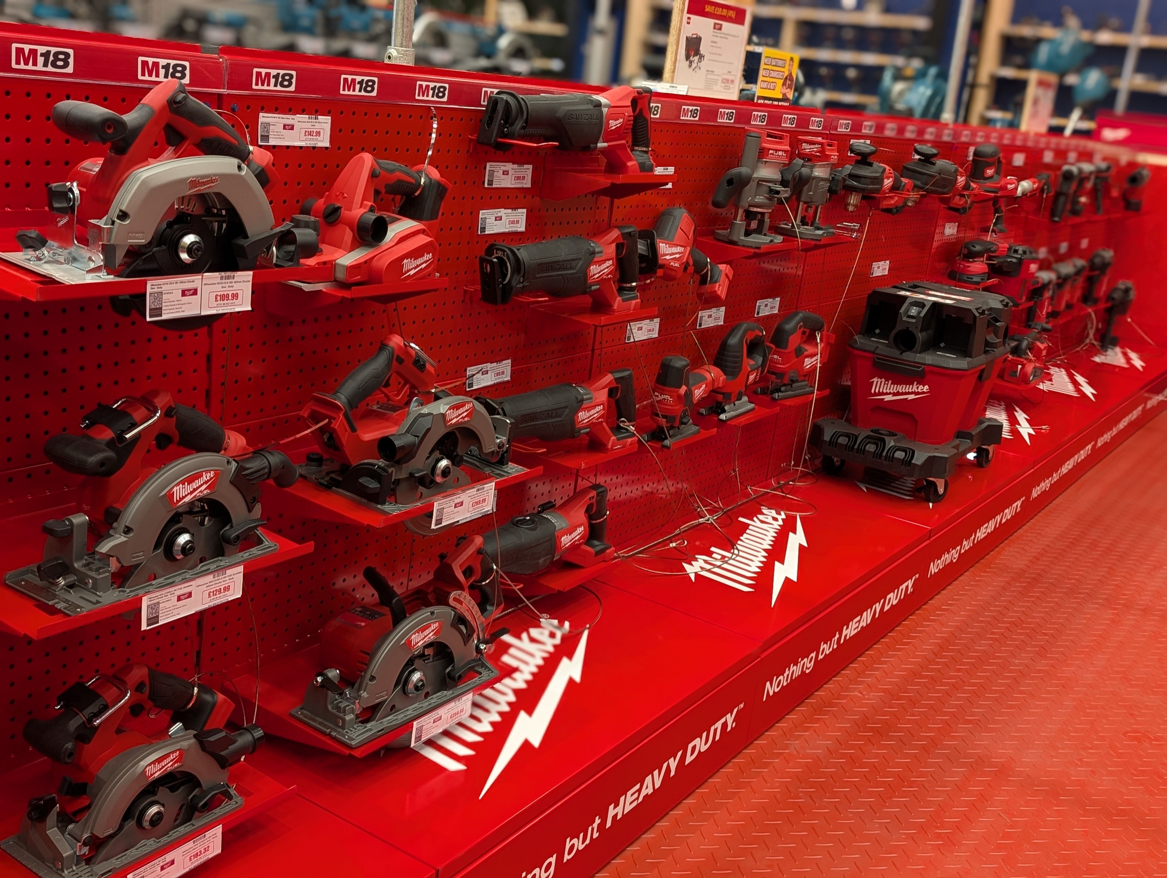 Display of various Milwaukee power tools on red shelves.