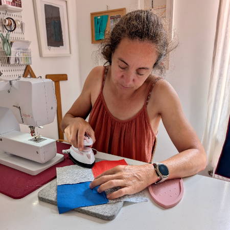 women pressing seams of a quilt block on a mini wool pressing mat