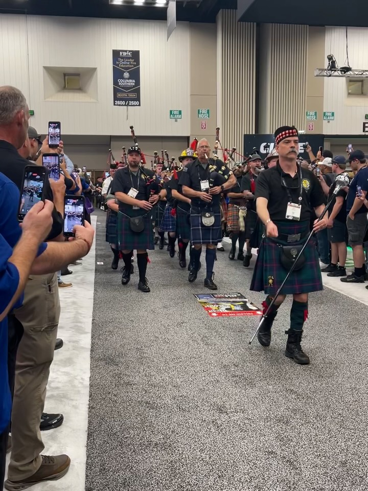 Bagpipers in kilts performing for an audience at an indoor event.