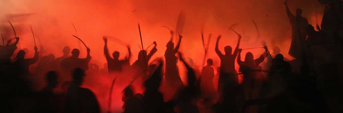 A group of people with raised weapons and fire in the background