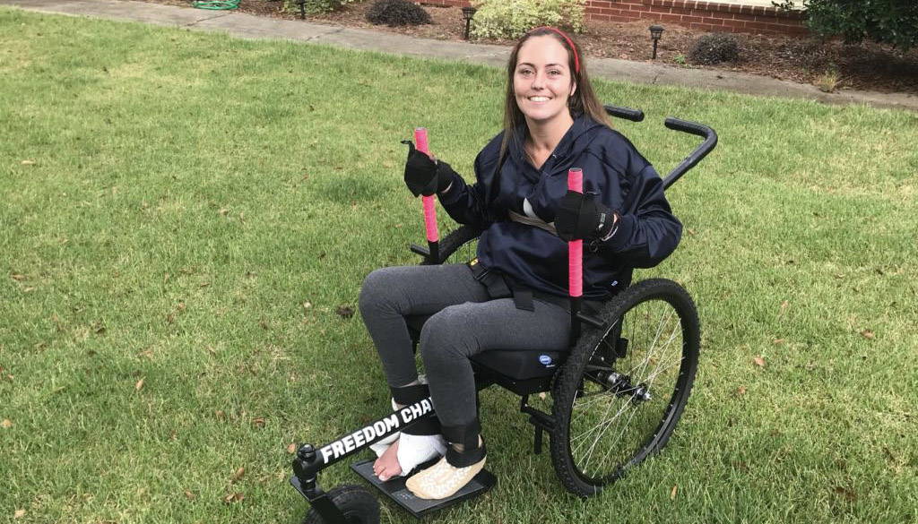 Person smiling using GRIT Freedom Chair off-road wheelchair on grass outdoors