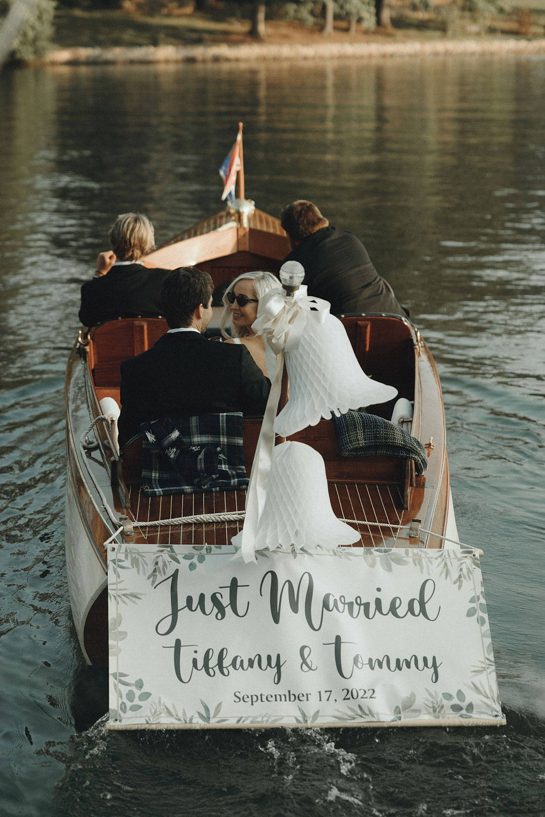 Braut und Bräutigam auf kleinem Boot mit "Just Married"-Schild an der Rückseite