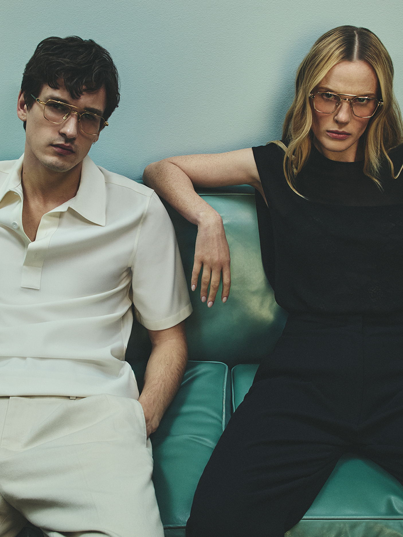 A man and a woman posing on a couch, both wearing Robert Marc glasses.