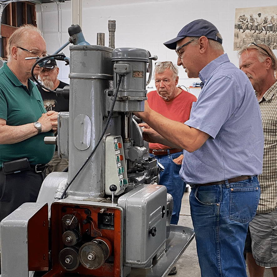Gear school attendees surround a Pfauter to learn the gear hobbing process