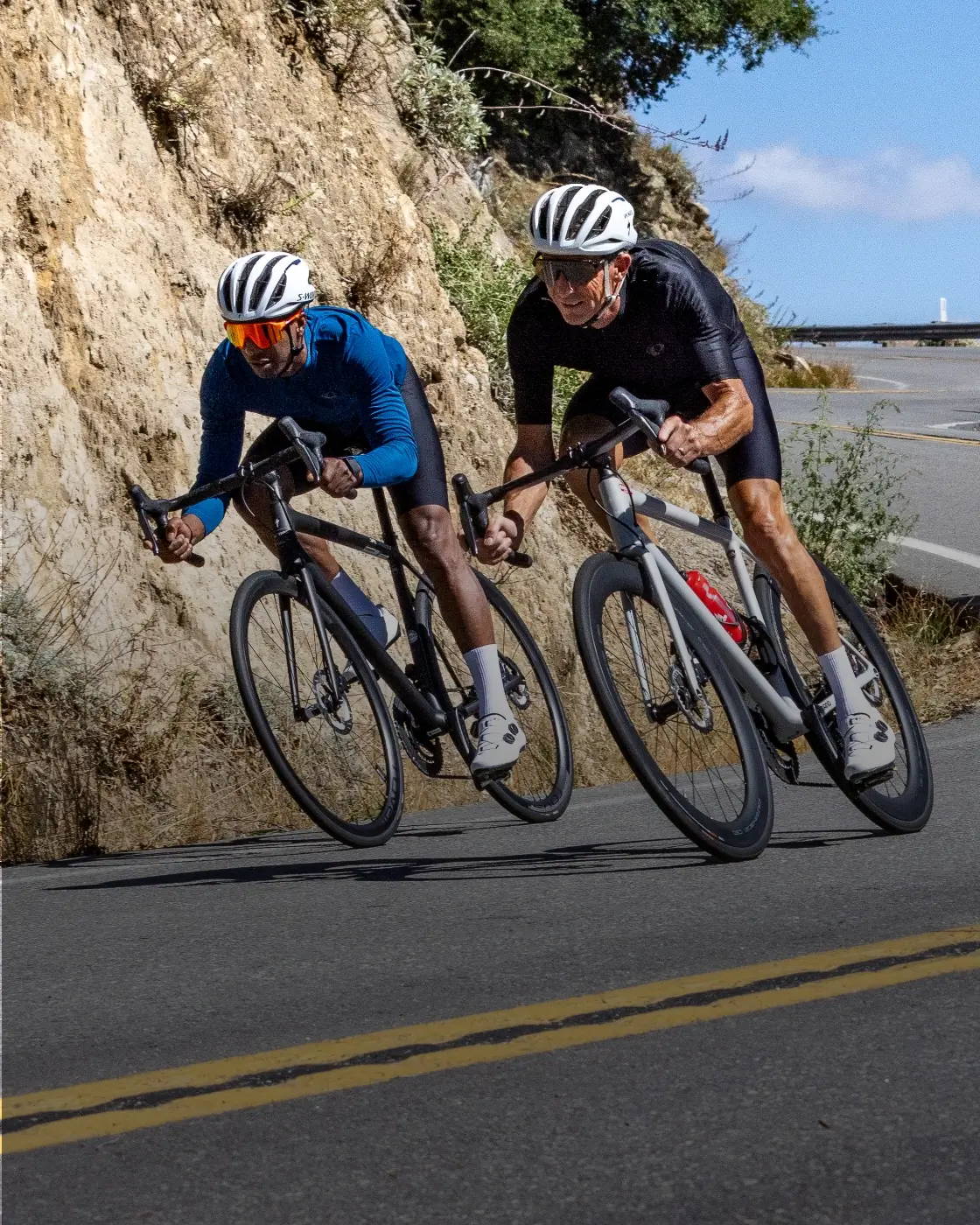 Two male road cyclist riding down a road wearing PEARL iZUMi's new Attack apparel