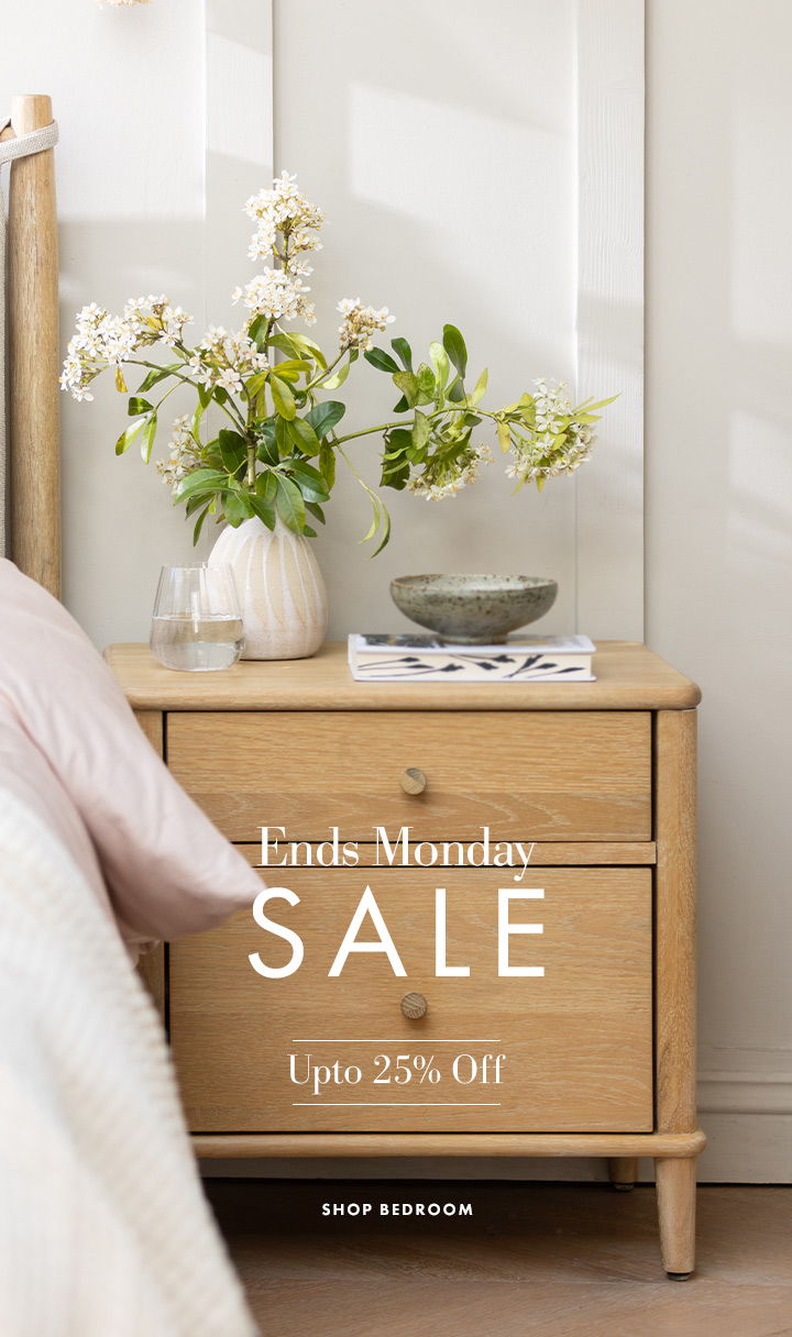 A wooden bedside table with flowers and a sale announcement.