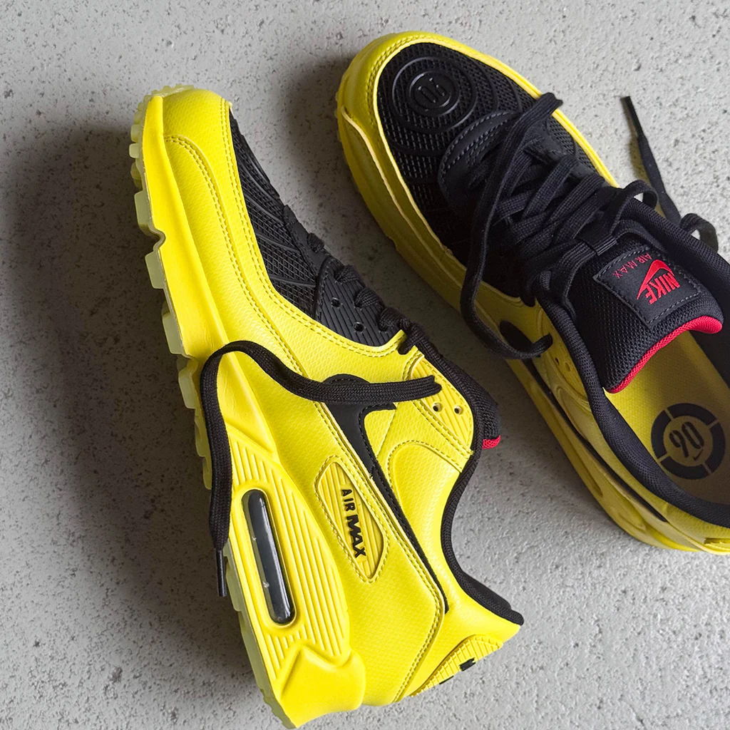 A pair of yellow and black athletic shoes on a gray surface.