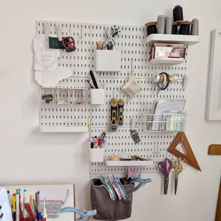 peg board on the wall with sewing tools and supplies