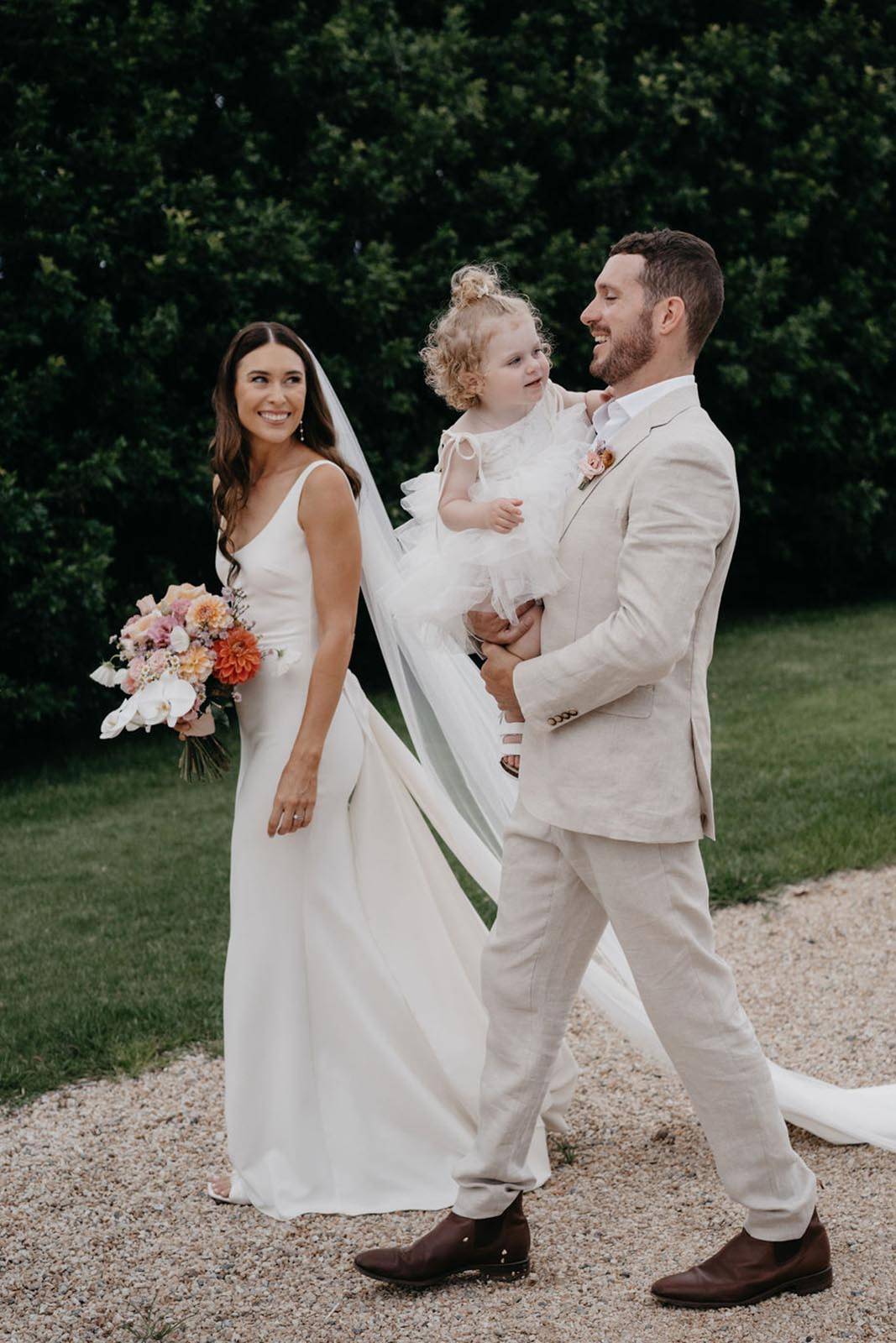 Heartwarming moment captured as the bride and groom are seen holding their daughter together. The groom is cradling his little girl in his arms