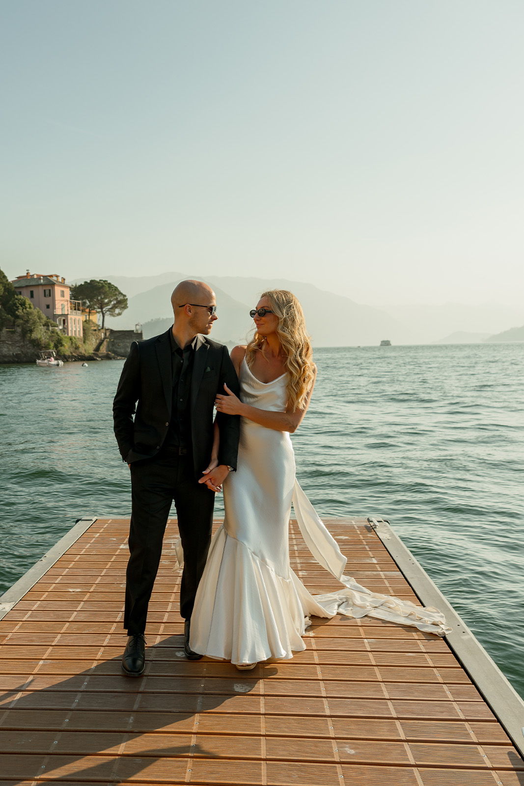 A couple in wedding attire on a dock by the water.