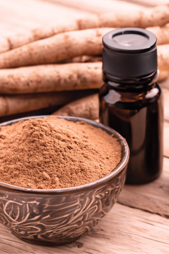 Bottles of oil, a bowl of powder, and roots on a wooden surface.