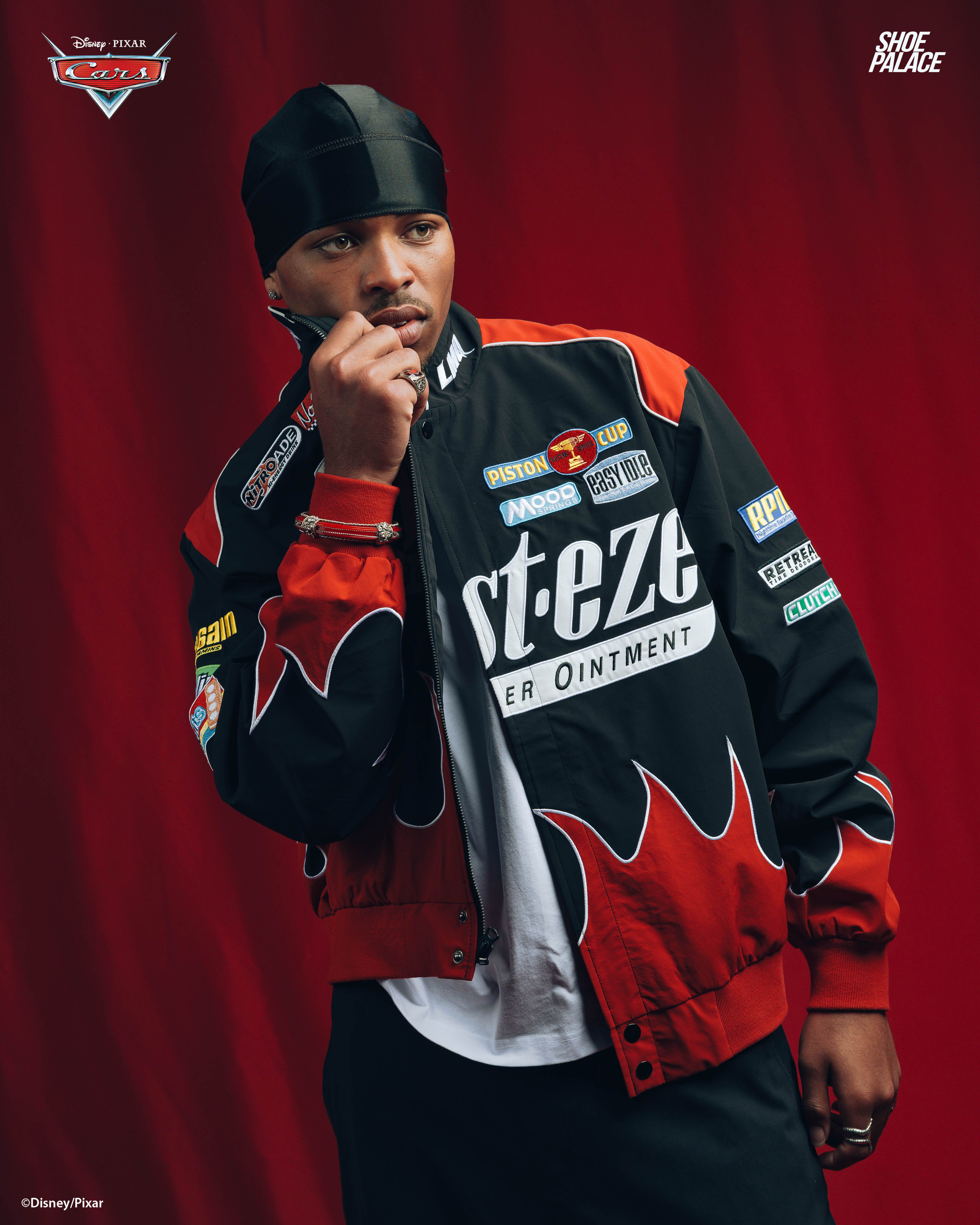 Person wearing a stylish jacket, posing against a red background.