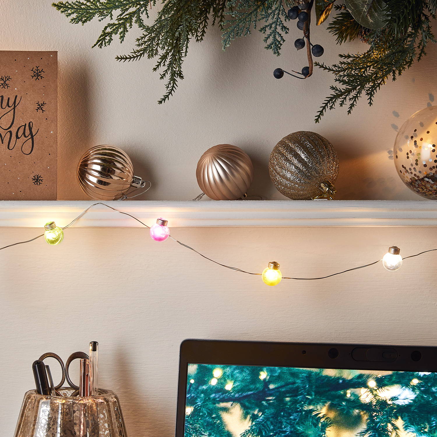 Multi coloured micro festoons draped across shelf above desk