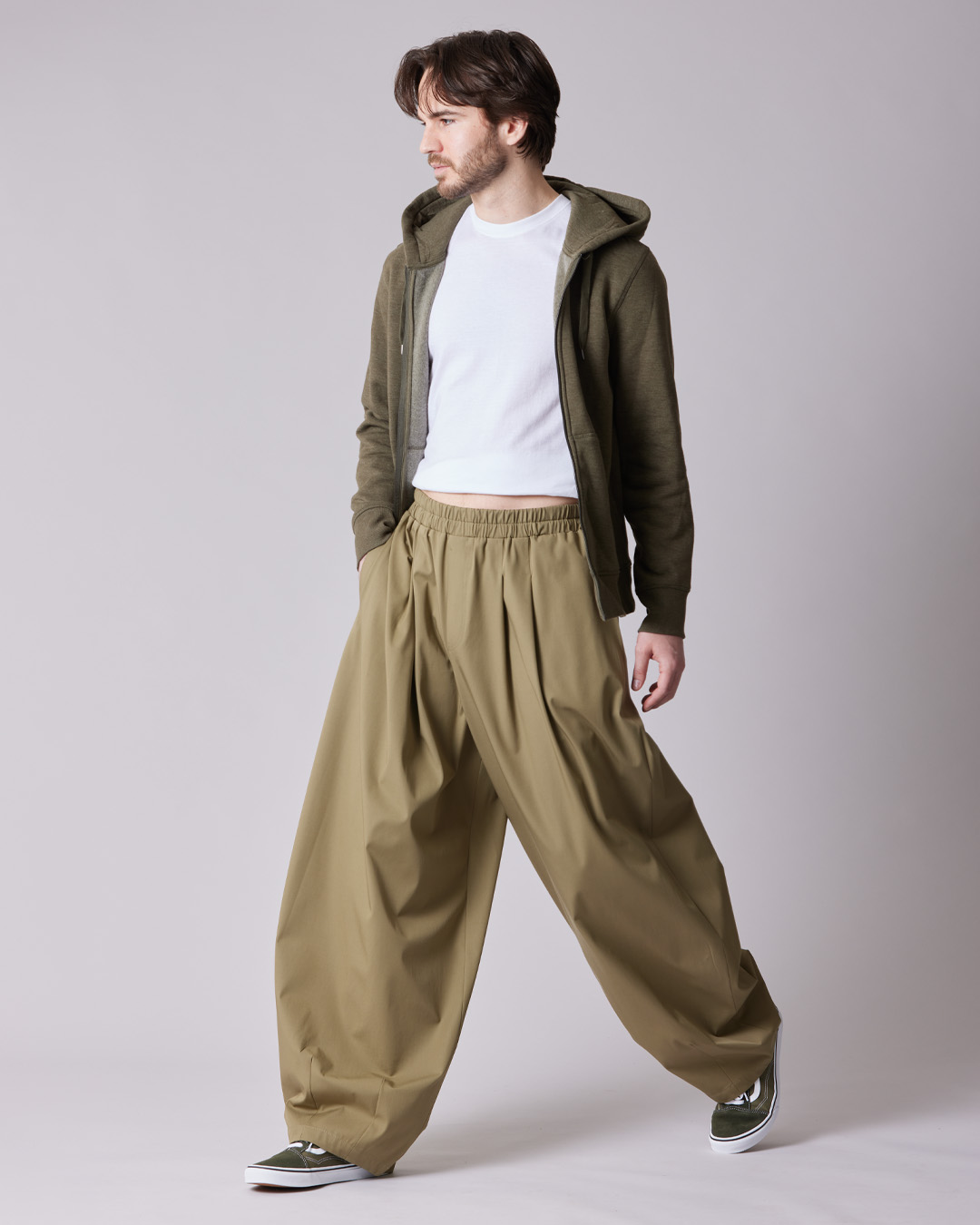 Man wearing oversized pants and a hoodie, posing against a neutral background.
