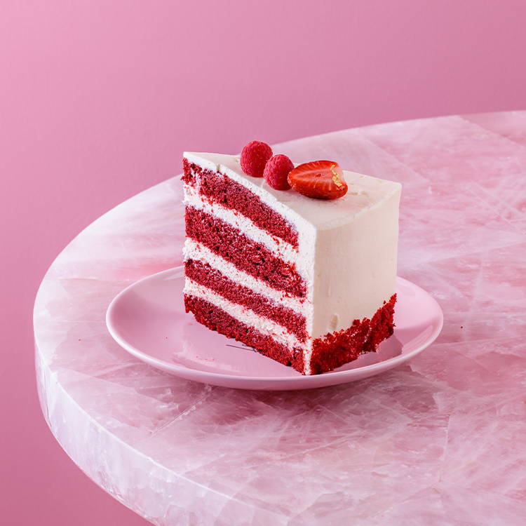 EL&N red velvet cake slice with fresh berries on pink plate