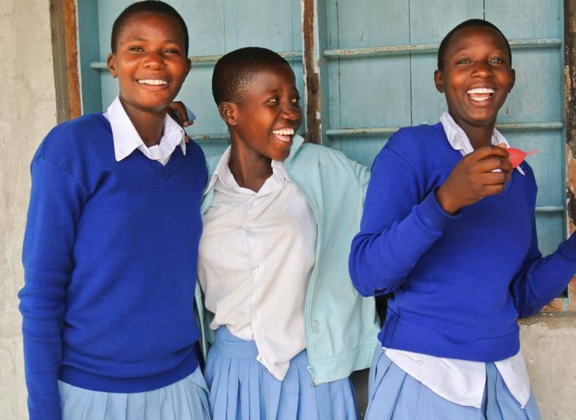 Girls wearing school uniform holding menstrual cups.