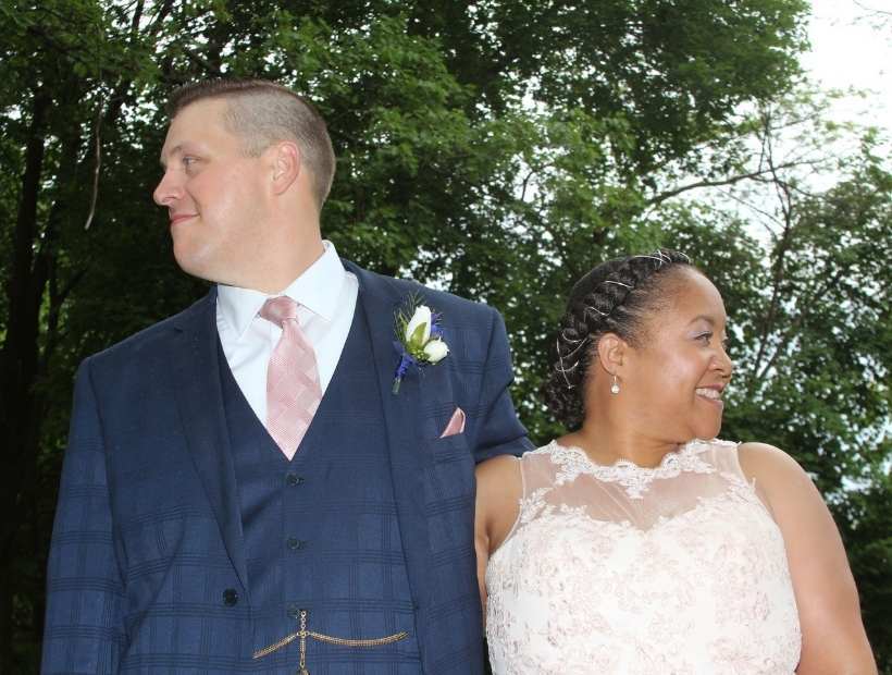 Bride and groom posing with a groom wearing a navy suit and pink tie