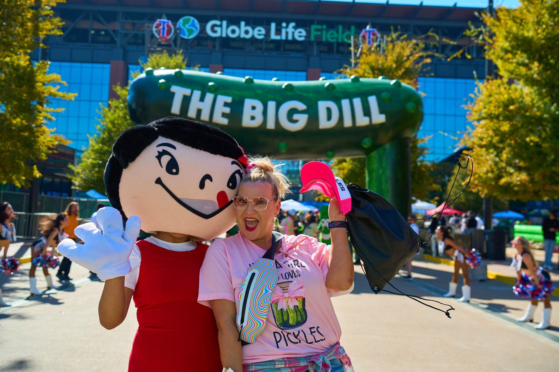 The Best Maid Pickles mascot poses with a guest in front of The Big Dill 30-foot inflatable pickle arch at Globe Life Field at The Big Dill pickle festival, Texas Live!, Arlington Texas 2025.