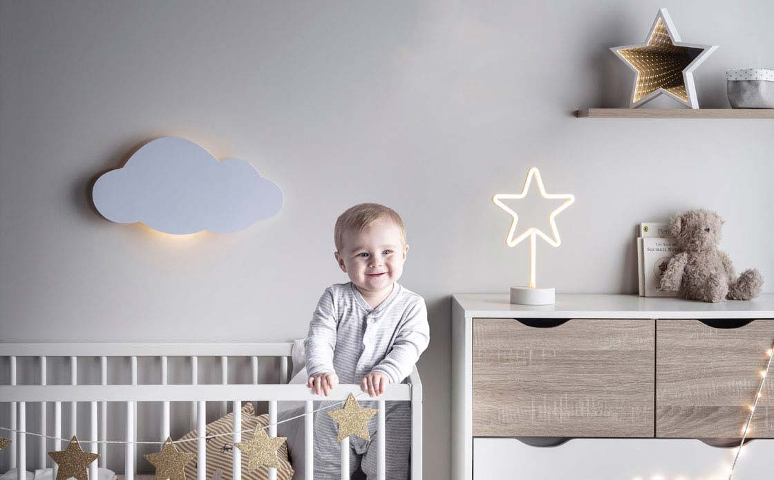 Baby in a cot surrounded by the nightsky collection