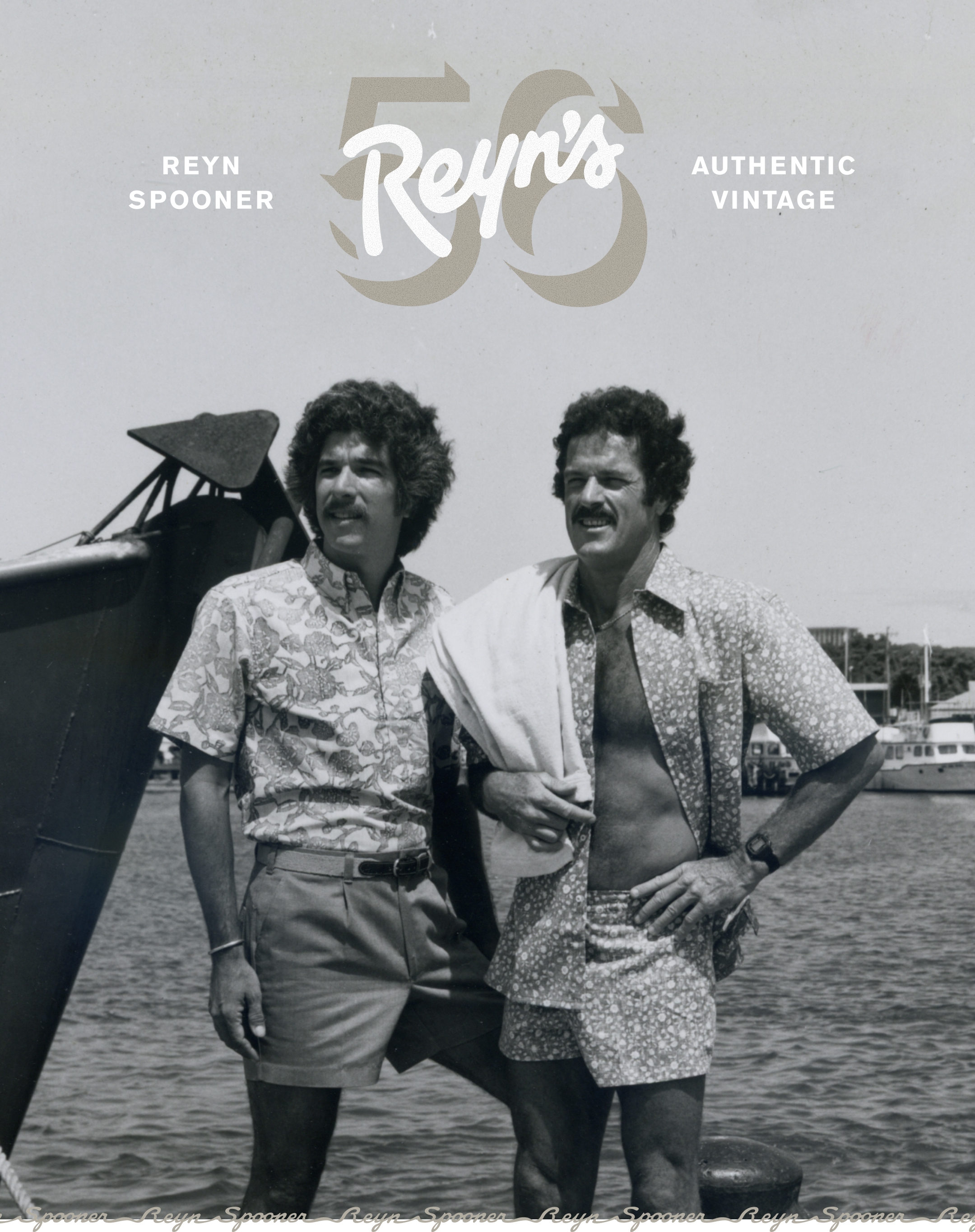 Two men posing by water, wearing shorts and patterned shirts.