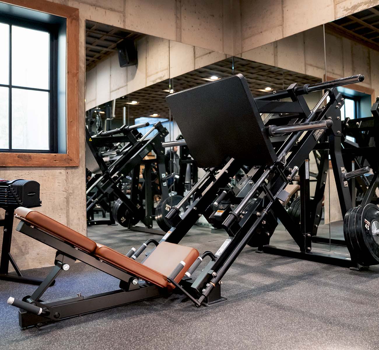 Hammer Strength Plate-Loaded Linear Leg Press in home gym, black frame / wheat upholstery