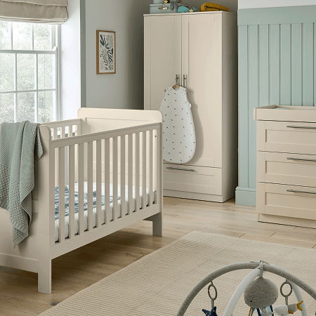 A cozy nursery with a crib, dresser, and wardrobe in soft colors.