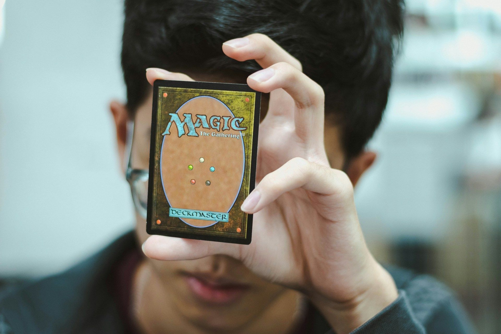 Person holding a card in front of their face, blurred background.