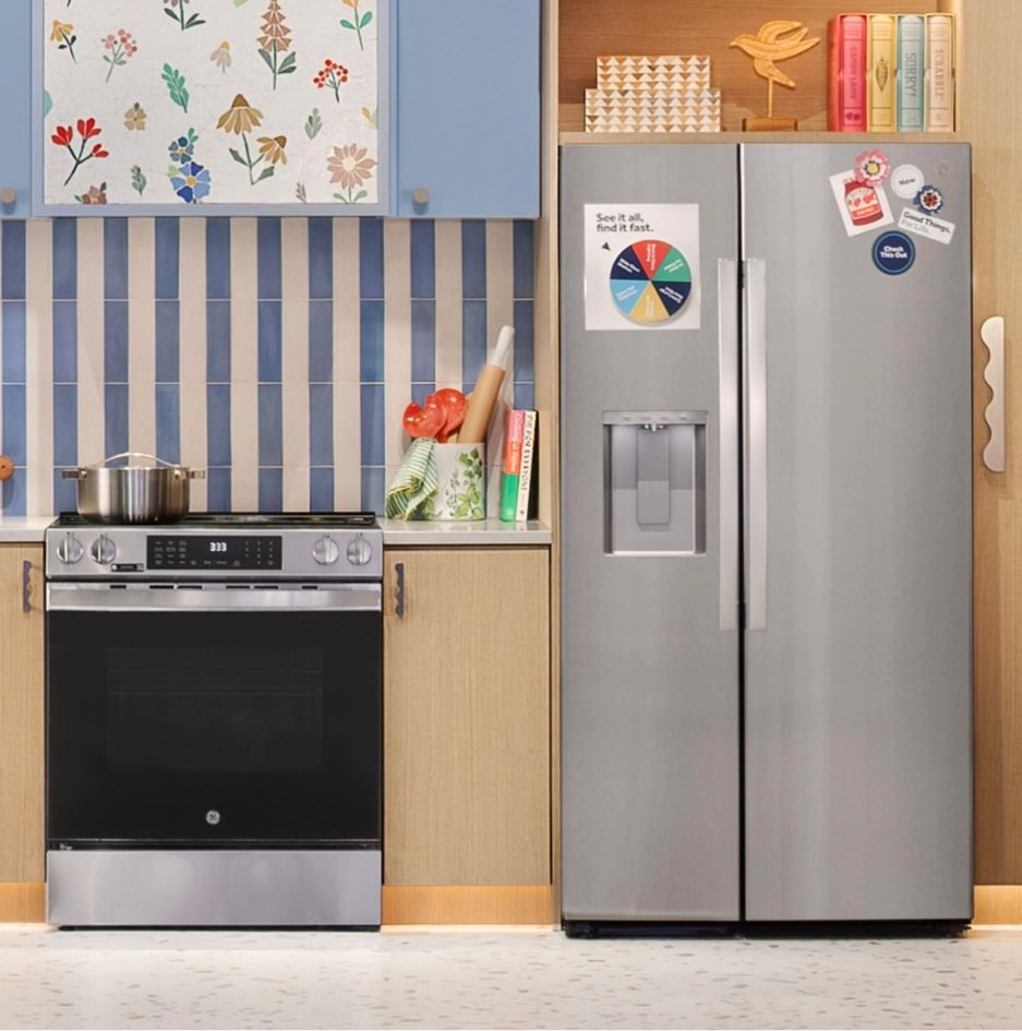 A kitchen with a silver refrigerator and black stove, colorful decor on walls.