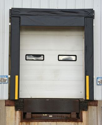 Loading dock with a white door and yellow safety markers.